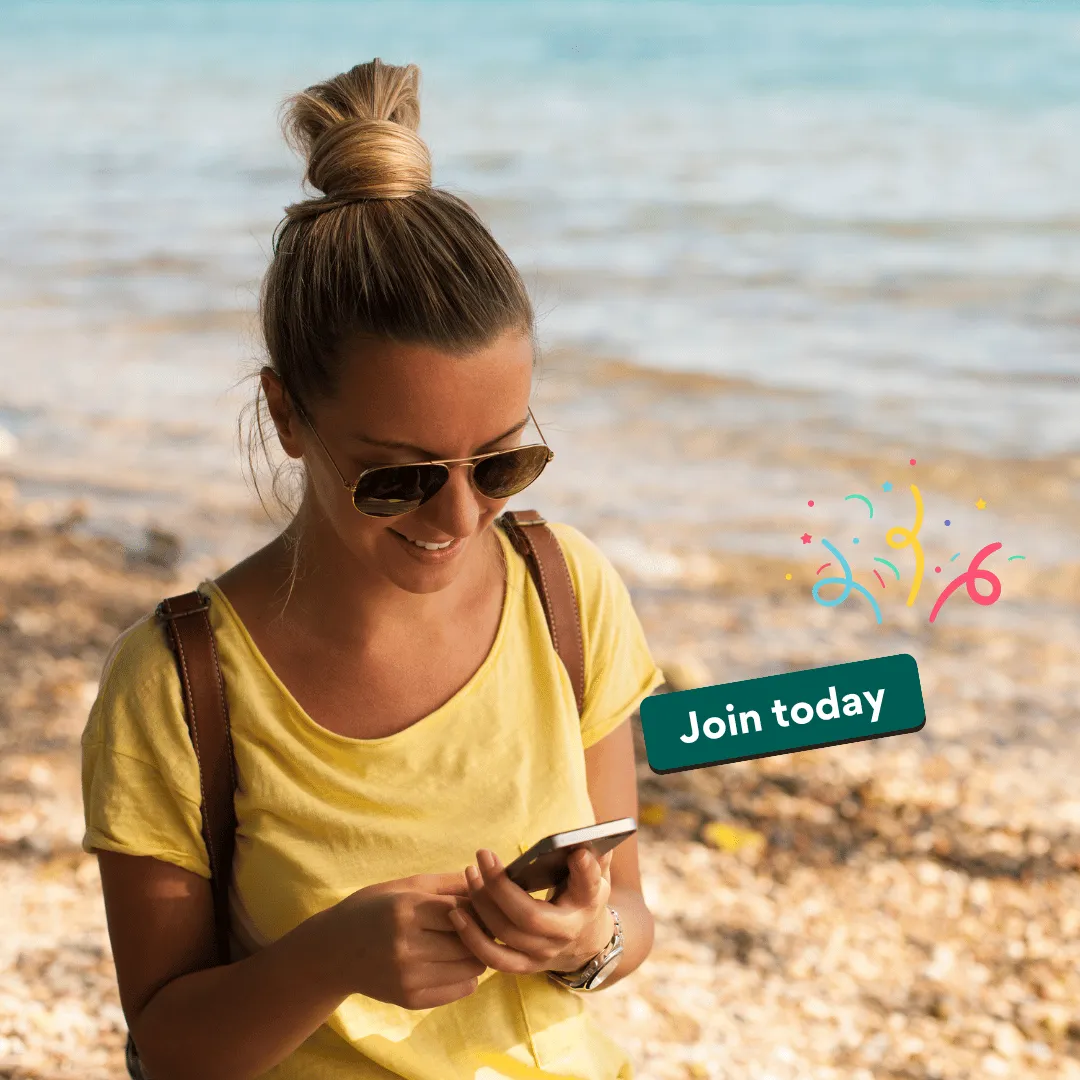 Excited woman at the beach holding her phone while applying for the TripLegend ambassador program